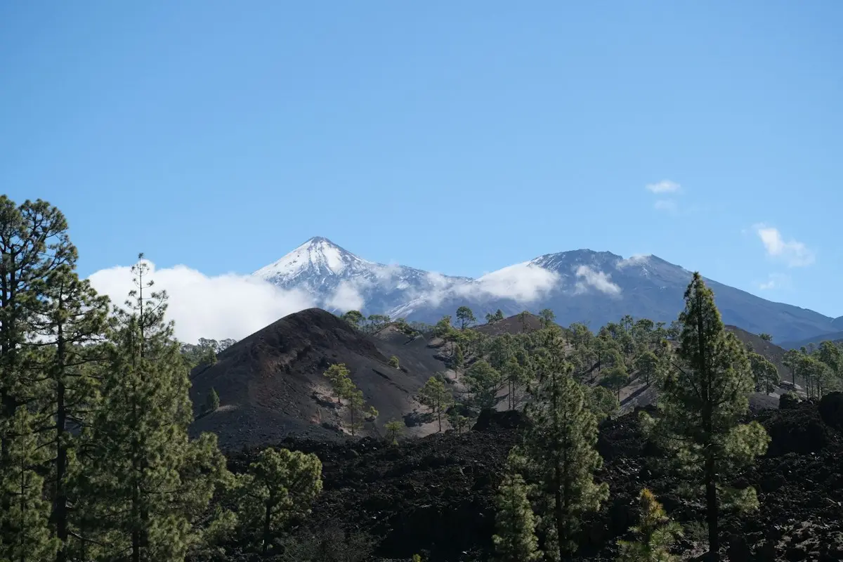 Schneebedeckter Teide über dunkler Vulkanlandschaft
